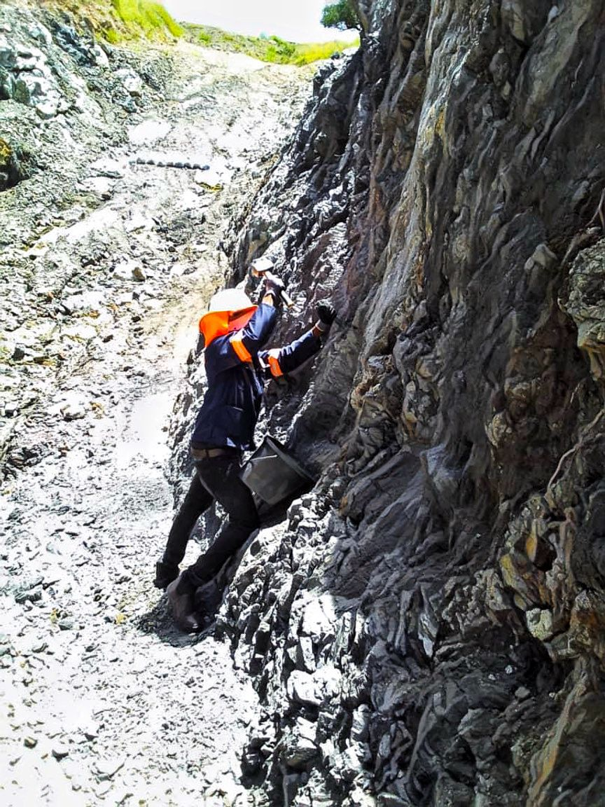 Field geologist examining exposed rock on the Graphitex project page footer panel